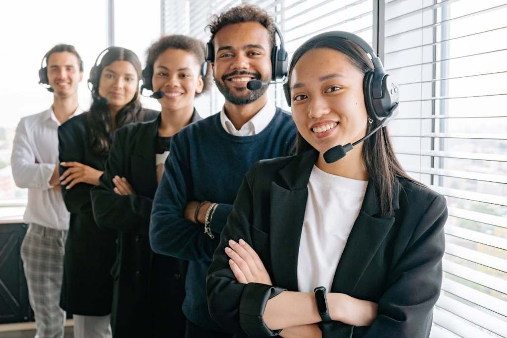 Call center agents with headphones smiling at the camera